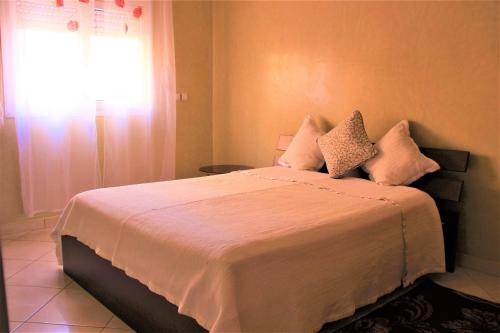 um quarto com uma cama com lençóis brancos e uma janela em luxury villa em Agadir