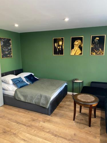 sypialnia z zielonymi ścianami, łóżkiem i stołem w obiekcie Apartament Błogi Sen- komfortowy nocleg w sercu Bytomia w Bytomiu