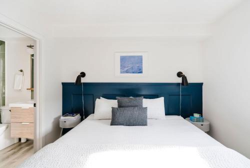 a bedroom with a blue headboard and a white bed at Mount Rundle Hideaway with Heated Pool & Hot Tub and allows Pets in Canmore