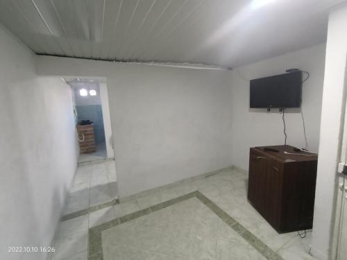 um quarto com uma televisão e uma parede branca em Hermoso apartamento independiente para pareja em Villavicencio