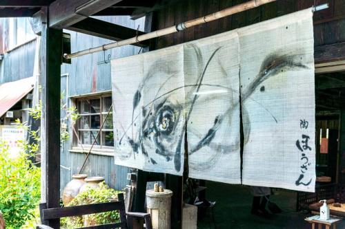 a painting of a dog on a sign on a building at 朝ドラのロケ地 信楽焼きの窯元に泊まれます 無料駐車場有 4人まで宿泊可能 in Nagano