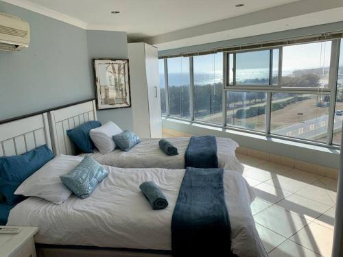 2 Betten in einem Zimmer mit einem großen Fenster in der Unterkunft Spacious 2 bedroom space with breathtaking seaview in Mossel Bay