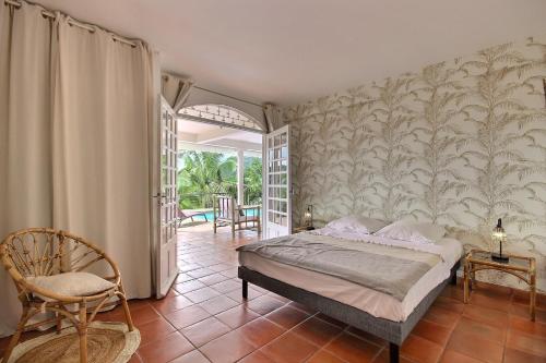 - une chambre avec un lit et une chaise dans l'établissement Villa Caluma, magnifique villa de 3 chambres avec piscine et vue mer, accès rapide au golf, Trois ilets, à Les Trois-Îlets