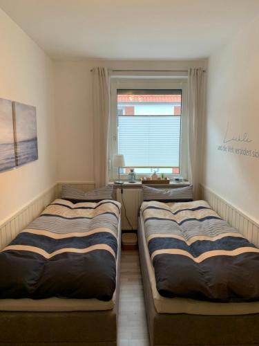 two beds in a room with a window at Ferienwohnung Engelke in Emden