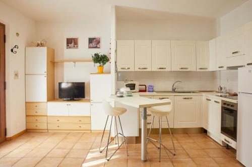 a kitchen with white cabinets and a table and stools at Conero - Patio Privato e Parcheggio by Host Hero in Marcelli