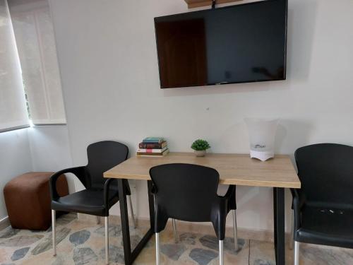 mesa con 4 sillas y TV en la pared en Envigado Parque Principal - Orquideas piso 3, en Envigado