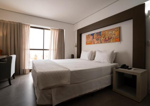 a bedroom with a large bed and a window at Hotel Cabo Branco Atlântico in João Pessoa