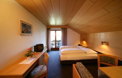 a hotel room with two beds and a television at Hotel Garní Sunnleit´n in Monguelfo