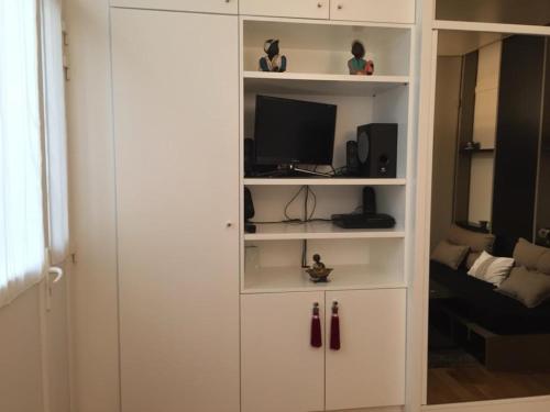 un meuble blanc avec une télévision et un salon dans l'établissement STUDIO COSY MONTPARNASSE, à Paris