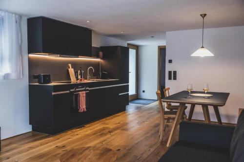 a kitchen with black cabinets and a table with chairs at Tante Anna Apartments in Sankt Gallenkirch