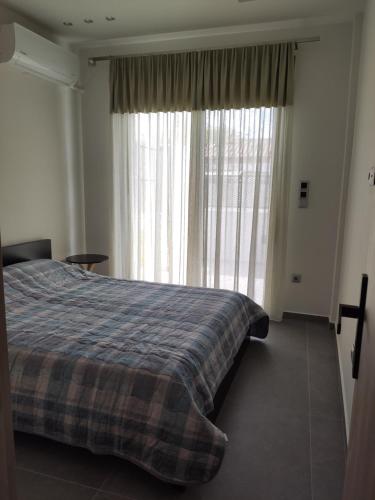 um quarto com uma cama e uma grande janela em Όμορφη οικία στο κέντρο της Σαλαμίνας. em Salamina