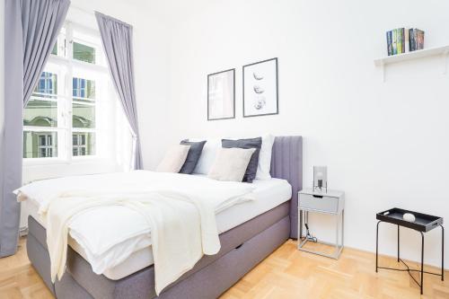 a white bedroom with a bed and a window at Bright Apartment in Old Town by Prague Days in Prague