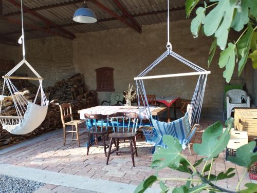 a patio with a table and chairs and swings at Helesfa Vendégház in Helesfa