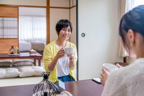 a woman is holding a cup in a room at 自然豊か棚田百選の棚田・道の駅・金剛山登山・釣り・ゴルフに便利/8名宿泊可広々一軒家/無料駐車場 in Tondabayashi
