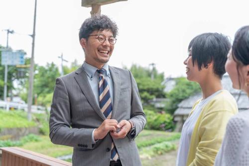 a man in a suit and tie shaking hands with a woman at 自然豊か棚田百選の棚田・道の駅・金剛山登山・釣り・ゴルフに便利/8名宿泊可広々一軒家/無料駐車場 in Tondabayashi