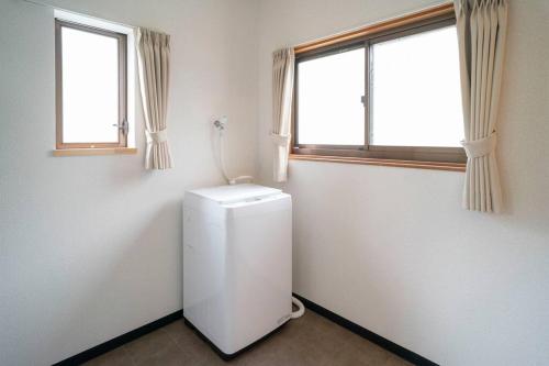 a small white refrigerator in a room with two windows at 自然豊か棚田百選の棚田・道の駅・金剛山登山・釣り・ゴルフに便利/8名宿泊可広々一軒家/無料駐車場 in Tondabayashi