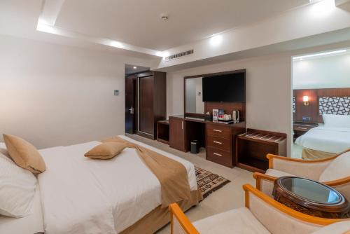 a hotel room with a bed and a chair and a television at Petra Elite Hotel in Wadi Musa