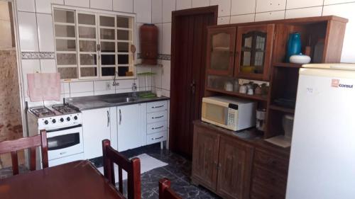 a kitchen with a white stove and a microwave at Raízes de Afrodite Kitnet in São Thomé das Letras