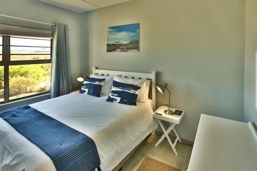 a bedroom with a bed with blue pillows and a window at Bella Casa in Langebaan