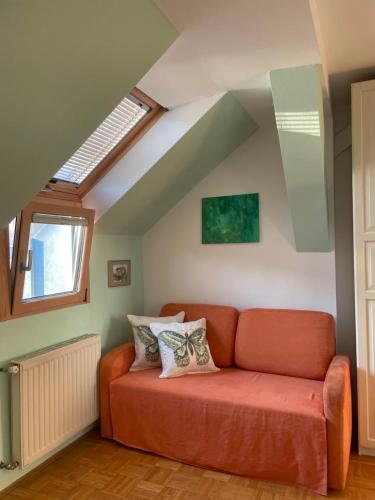 an orange couch in a living room with a window at Grazer Schwalbe in Graz