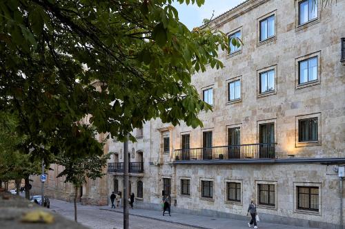 - un grand bâtiment en pierre avec des personnes marchant devant dans l'établissement Inés Luna Suites, à Salamanque