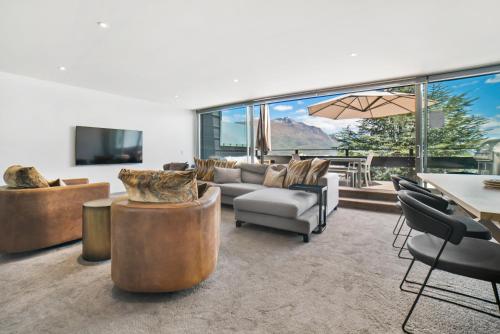 Una sala de estar con un sofá y sillas y una mesa. en Luxury Penthouse P2, en Queenstown