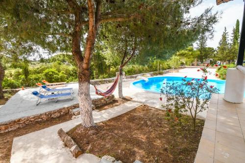 a tree with a hammock next to a swimming pool at Elatia Villa in Volimes