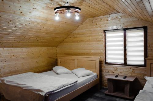 Cette chambre comprend un lit dans une cabane en bois. dans l'établissement La Maria si Ioana, à Curtea de Argeş