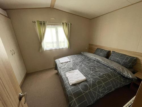 a bedroom with a bed and a window at Holiday park caravan Fluffy in Harts Holiday Park in Leysdown-on-Sea