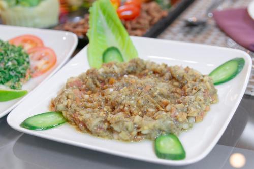 a plate of food with meat and vegetables on a table at Petra Elite Hotel in Wadi Musa