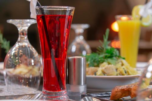 a red glass sitting on a table with a plate of food at Petra Elite Hotel in Wadi Musa