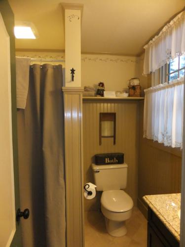 a bathroom with a toilet with a shelf above it at Covered Bridge House in Glen