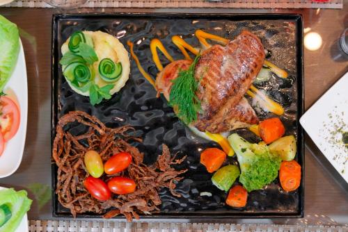 a plate of food with meat and vegetables on a table at Petra Elite Hotel in Wadi Musa