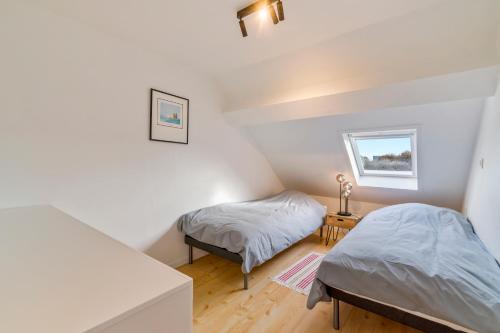 twee bedden in een kamer met witte muren en houten vloeren bij Duinenhuisje in Oostende