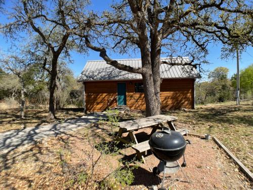 a grill and picnic table in front of a log cabin at Walnut Canyon Cabins in Fredericksburg