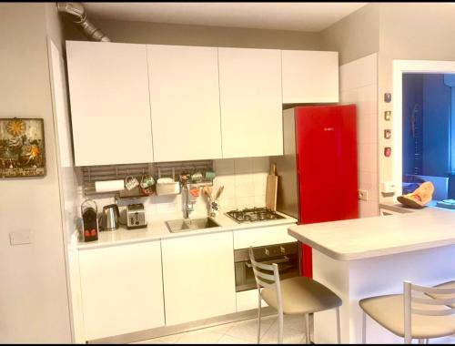 uma cozinha com armários brancos e um frigorífico vermelho em Casa Ginestra Mare em Bordighera