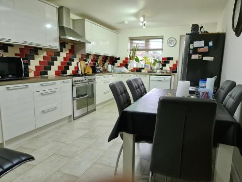 cocina con mesa, sillas y nevera en Homely Home en Buckinghamshire