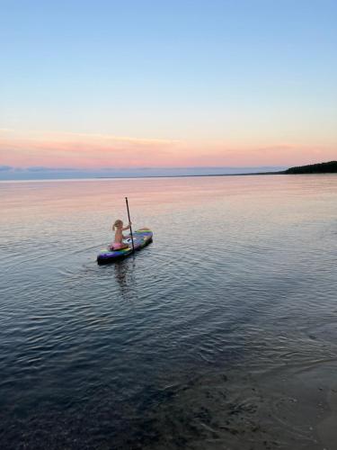 a person in a paddle boat on a body of water at Albatross Beach Apartment - SPA, Sea and Forest in Ķesterciems