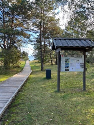 a sign next to a boardwalk in a park at Albatross Beach Apartment - SPA, Sea and Forest in Ķesterciems