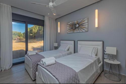sypialnia z 2 łóżkami i dużym oknem w obiekcie Avithos Blue Villas w mieście Svoronata