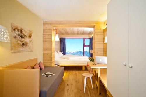マソ・コルトにあるGlacier Hotel Grawandのソファ、ベッド、デスクが備わる小さな客室です。