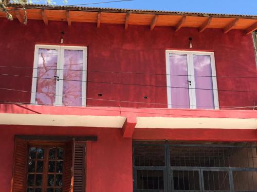 a red building with three windows on it at El Descanso Housse II in San Miguel de Tucumán