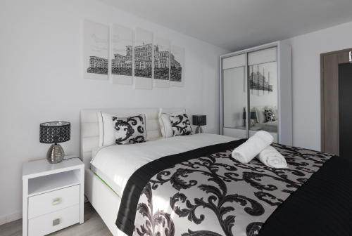a black and white bedroom with a bed and a nightstand at Lion's Unirii Apartment in Bucharest