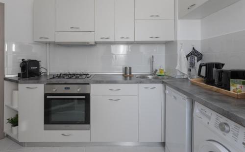 a white kitchen with a stove and a sink at Lion's Unirii Apartment in Bucharest