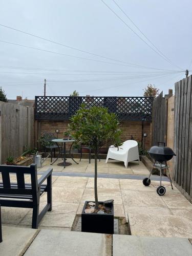 a garden with a tree and a grill and a bench at Avocet House Hunstanton 250m from the sea in Hunstanton