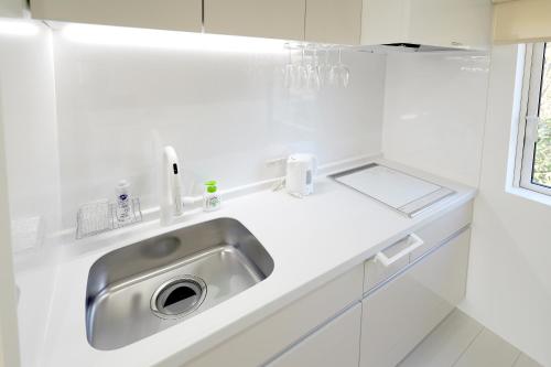 uma cozinha branca com um lavatório de aço inoxidável em NISEKO EPIC HOUSE em Niseko