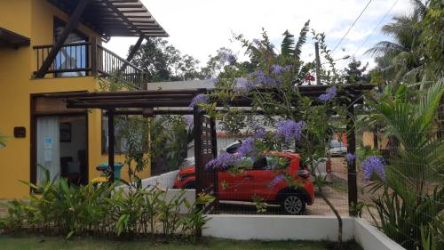 a red car parked in front of a house with purple flowers at Conchas do Mar Residence in Itacaré
