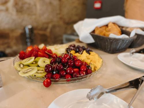 a table with a plate of fruit on a table at Casa das Muralhas in Covilhã