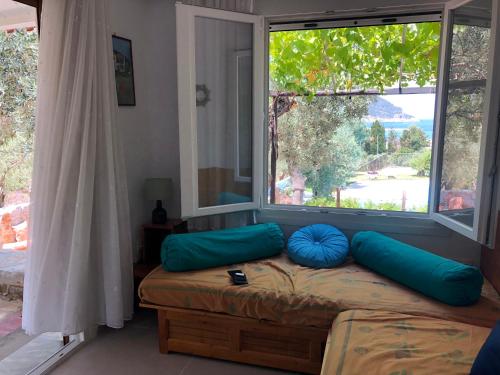 a bedroom with a bed with blue pillows and a window at Del & Sol in Skopelos Town