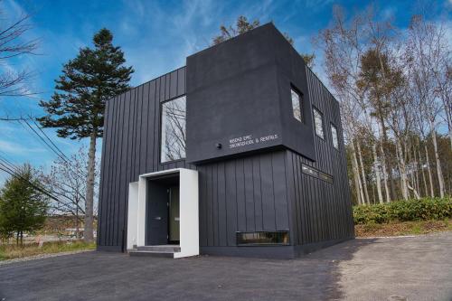 a black building with a door in a parking lot at NISEKO EPIC HOUSE in Niseko